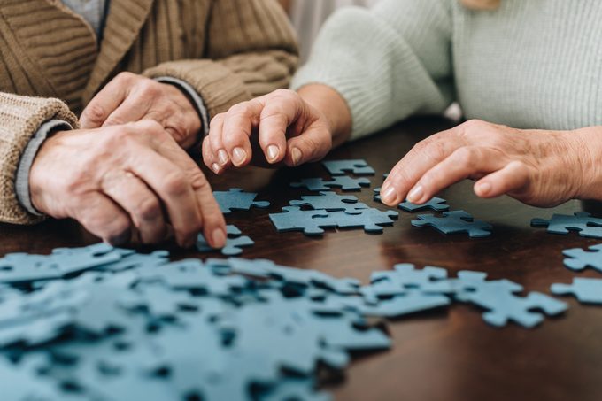 cropped view of retired couple playing with puzzles at home