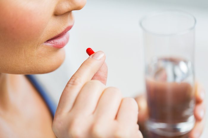 Close up of woman taking in pill.