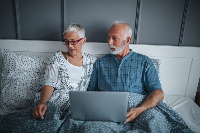 Mature couple using laptop while in bed