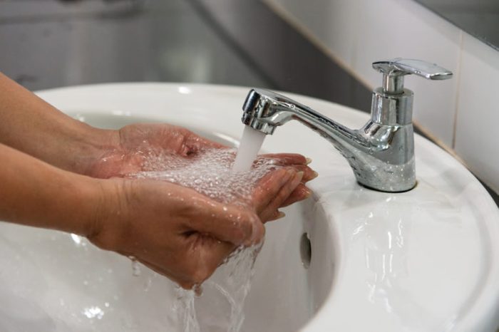 Close up woman hand washing under running water in the toilet.Hand hygiene concept.