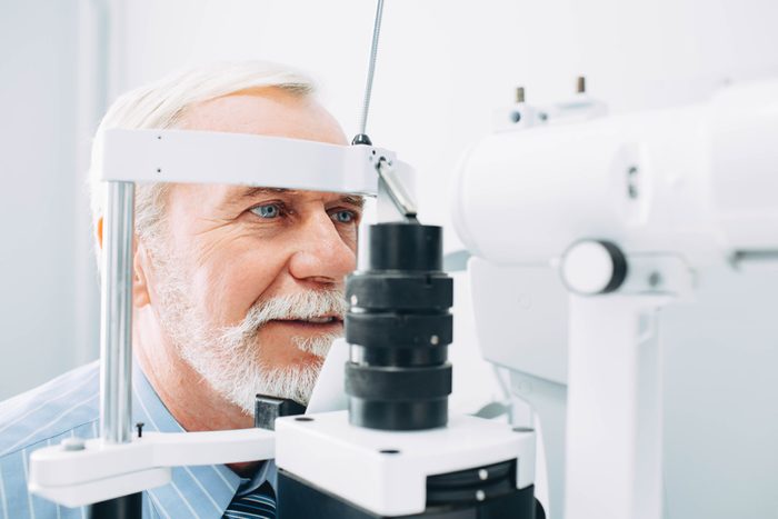 Senior man receiving eye exam at clinic, eyesight examination aged people
