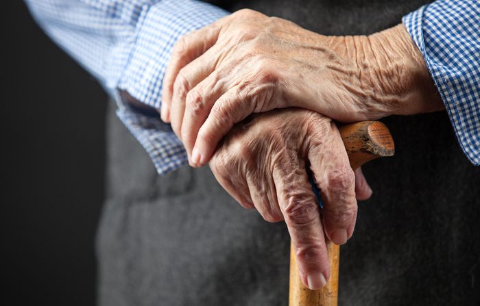 Closeup of senior woman's hands on wooden walking stick 