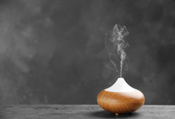 Aroma oil diffuser on table against grey background. Air freshener