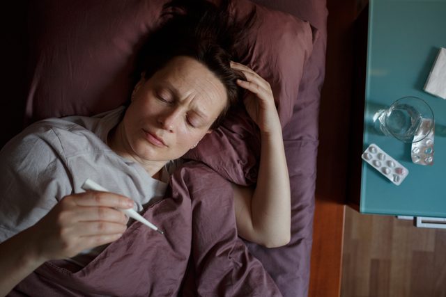 woman laying in bed with fever