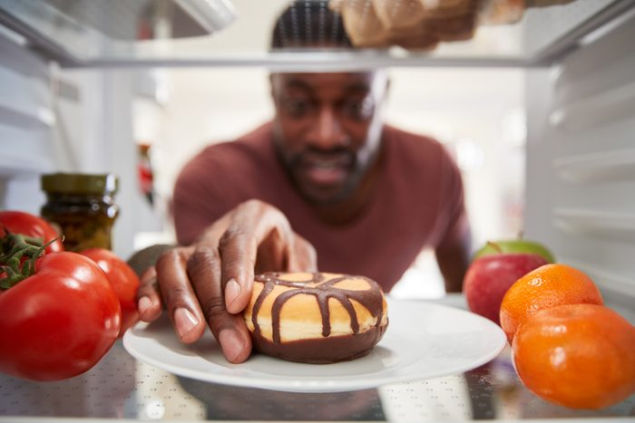 view from inside of refrigerator as man reaches for donut