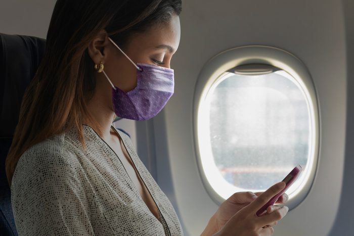 woman sitting on airplane with face mask on