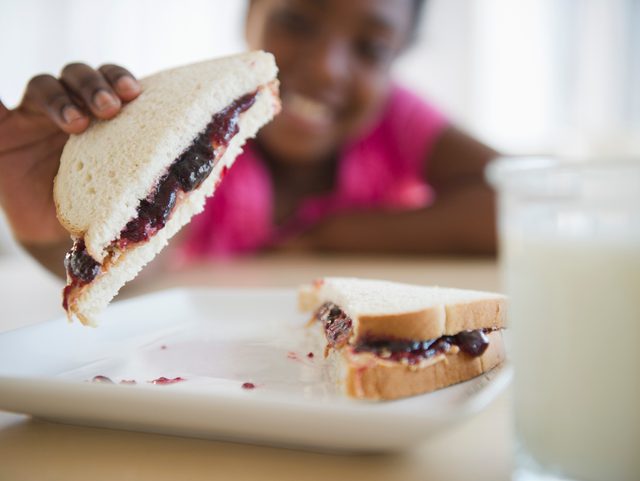 little girl holding peanut butter and jelly sandwhich