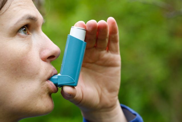 close up of woman using inhaler