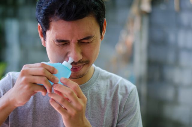 man using a saline nasal rinse device