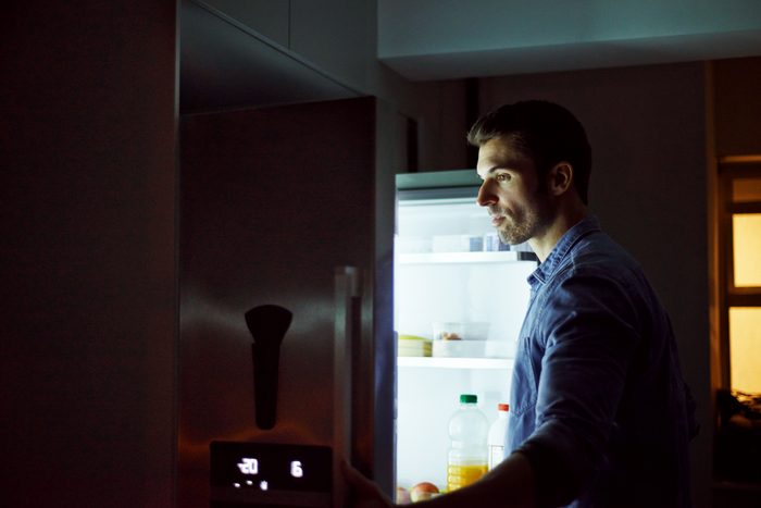man looking in refrigerator at night