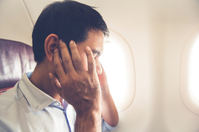 Male man airline flight passenger having ear pop on the airplane while taking off