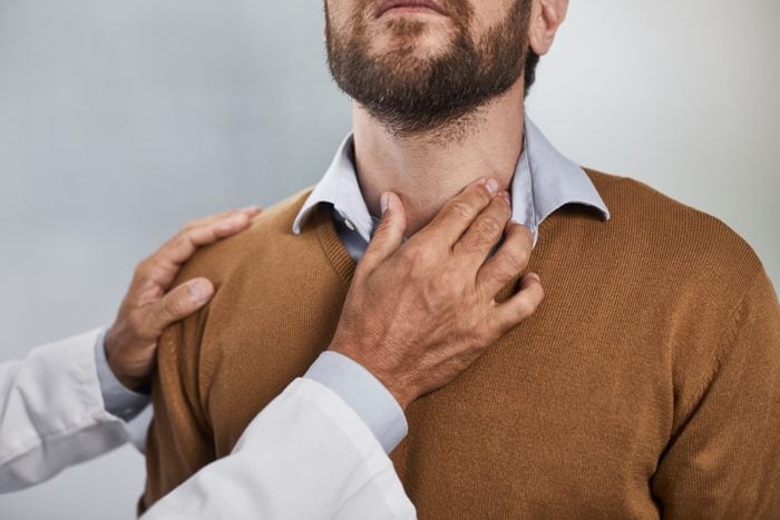 doctor's hand touching a man's neck