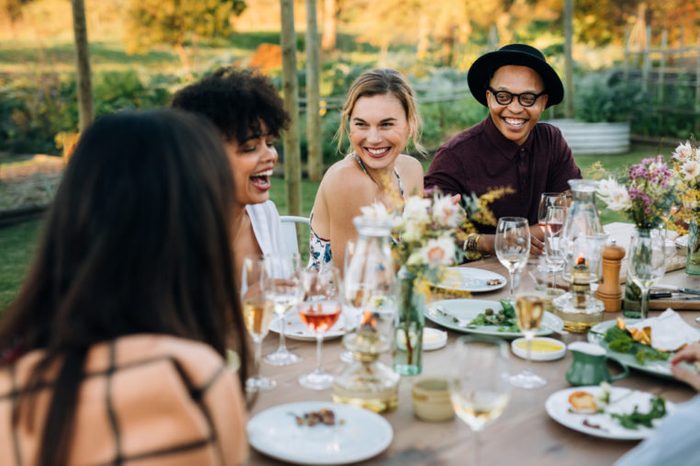 Group of friends enjoying outdoor party in home garden. Millennials enjoying summer meal at restaurant.