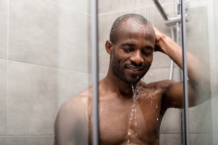 handsome smiling african american man with closed eyes taking shower