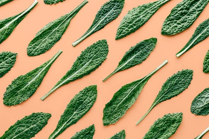 Fresh organic green kale leaves pattern on a pastel peach background, flat lay healthy nutrition concept