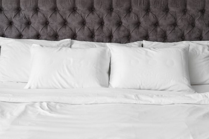Soft white pillows on comfortable bed, closeup.