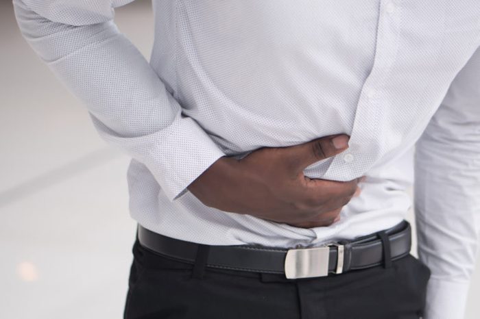 A man holding his stomach as if having a stomachache.