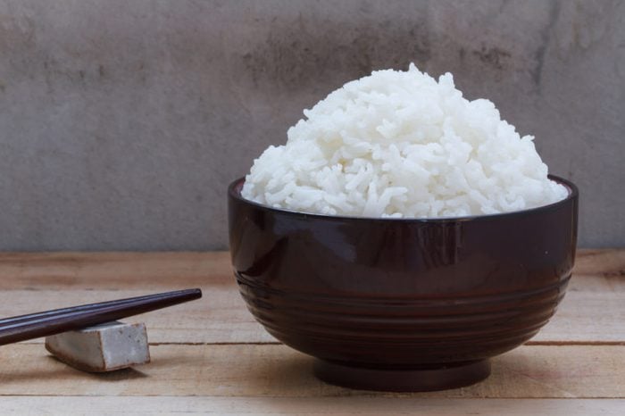 Cooked rice in bowl on wood background.