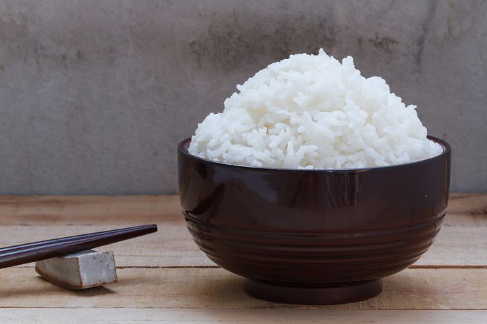 Cooked rice in bowl on wood background.