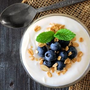 Yogurt with sweet blueberries and granola, above view on rustic dark wood