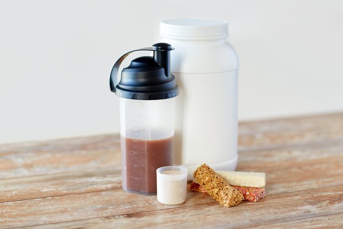 Protein shake bottle and muesli bars on wooden table.