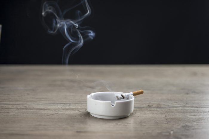 Lit cigarette burning in ashtray close up