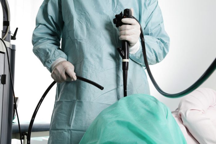 Doctor in hospital scrubs holding endoscope before colonoscopy.