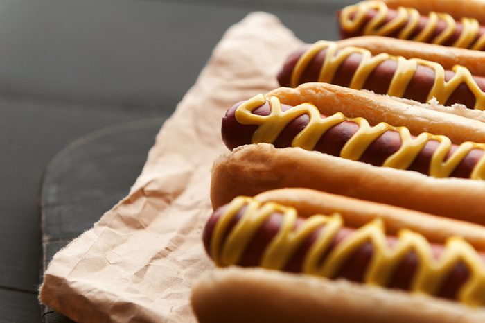 Barbecue Grilled Hot Dogs with yellow American mustard, On a dark wooden background