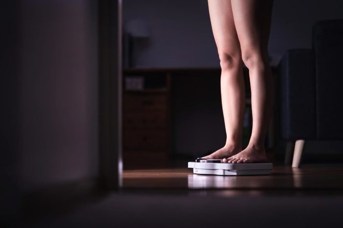 Close up of woman's legs standing on a scale