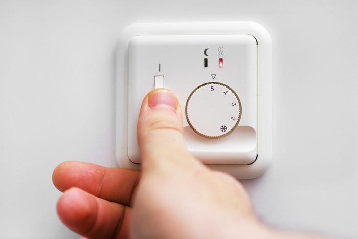 person adjusting a thermostat