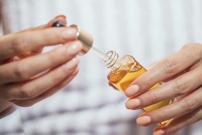 hands holding a dropper in a bottle of oil