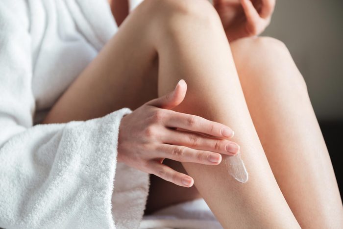 woman putting lotion on her leg