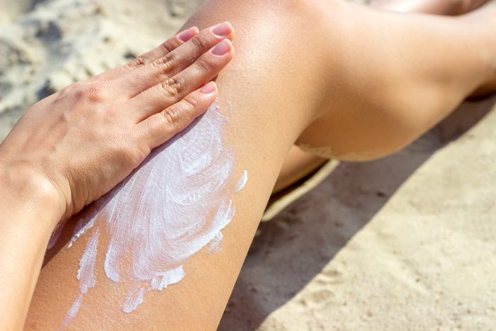 close up of woman applying sunscreen to leg
