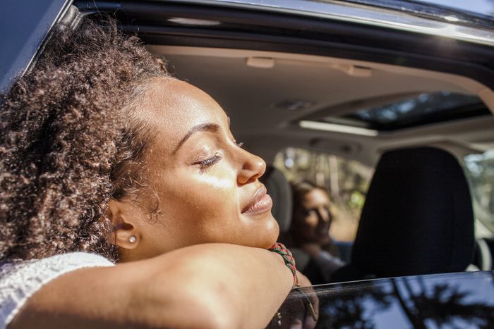 woman with head out of car window soaking up the sunshine