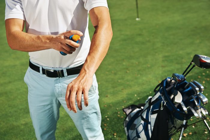 man applying sunscreen while playing golf