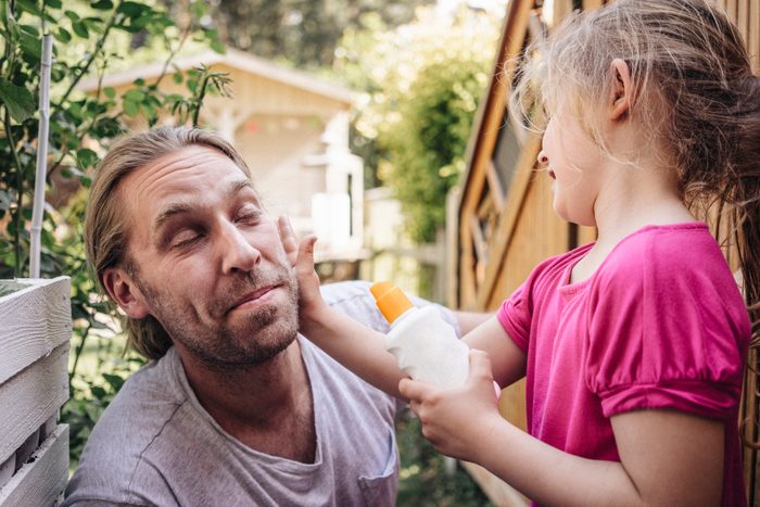 young girl applying sunscreen on her father's face