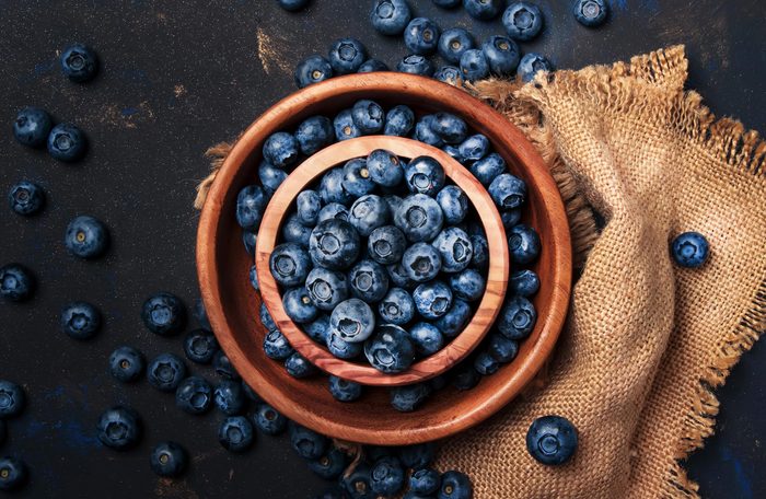 Fresh blueberries in wooden bowl on dark kitchen table background, copy space, top view