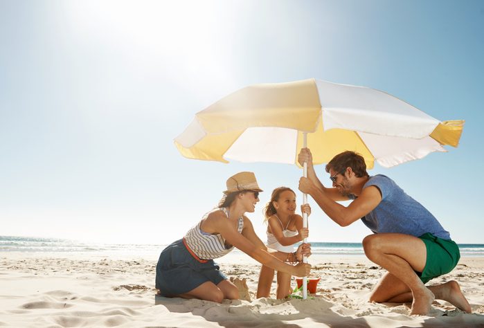 family setting up umbrella at beach