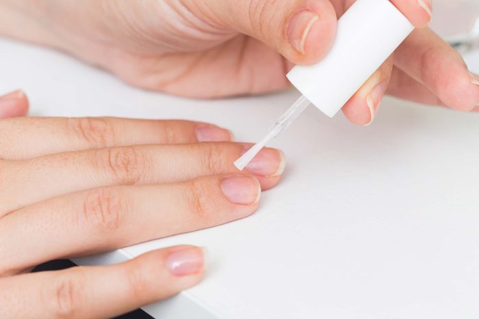 woman painting clear polish on nails
