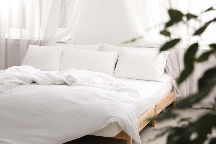 an unmade bed with white linens