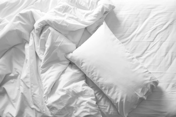 unmade bed with pillow and sheets