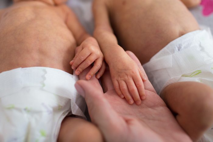 mother holding premature twins hands