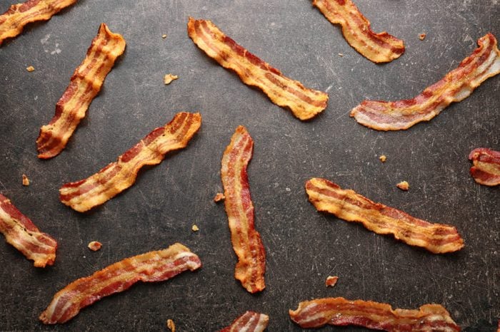 Strips of fried bacon on gray background