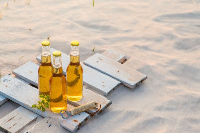 Three beer bottles standing on the rustic wooden board