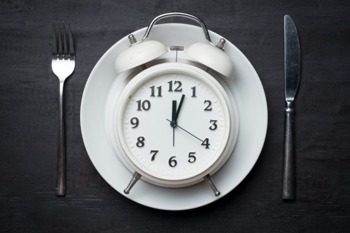 Weight loss or diet concept,Alarm clock on plate with knife and fork on wood