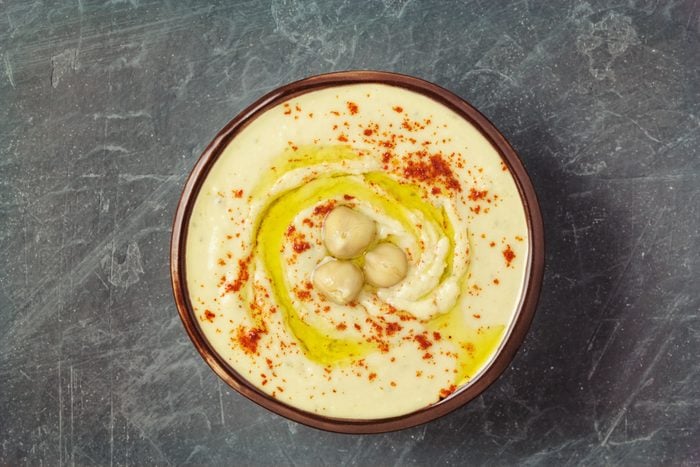 Bowl of fresh hummus topped with swirl of olive oil, paprika, and garbanzo beans