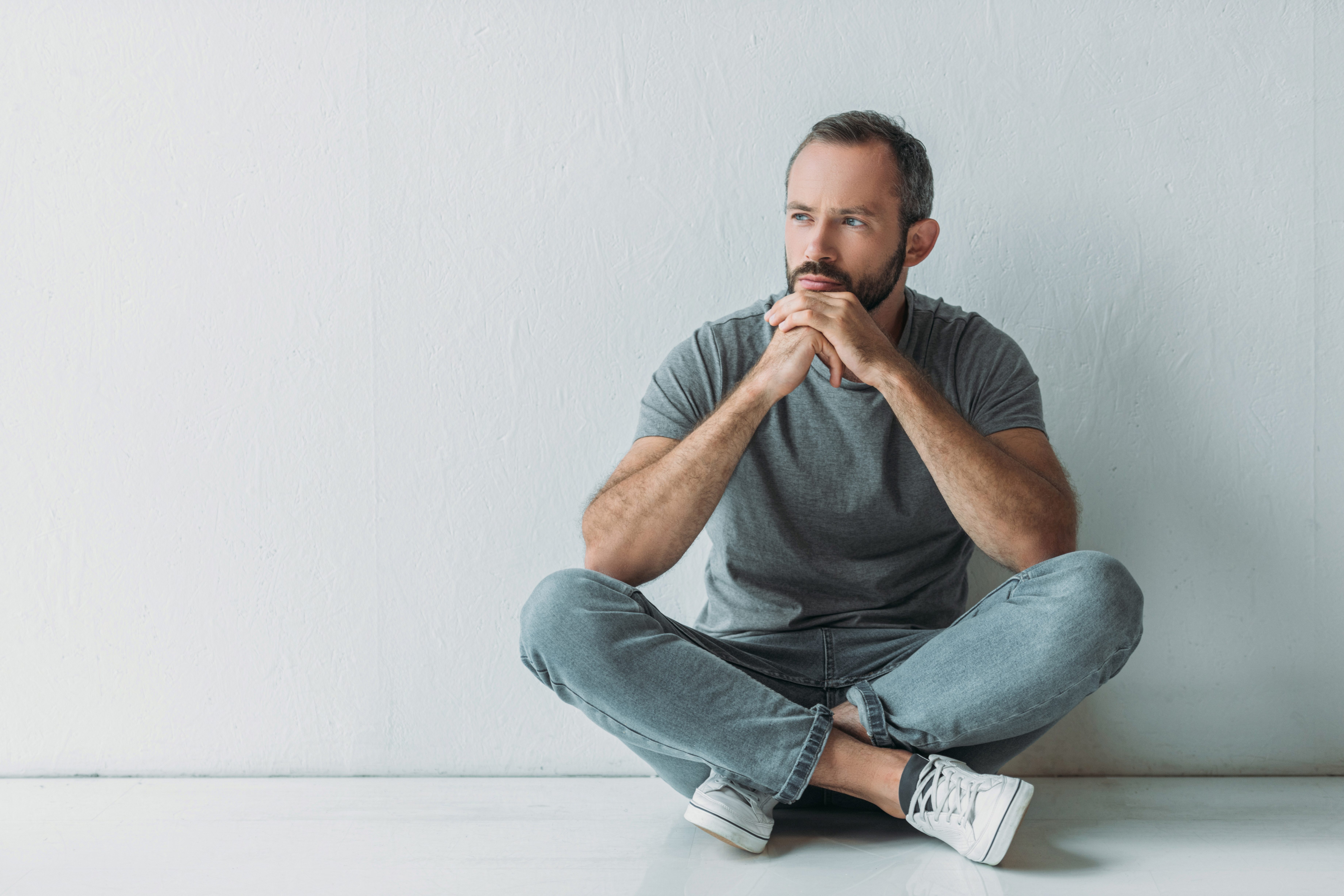 unhappy bearded man sitting in floor and looking away