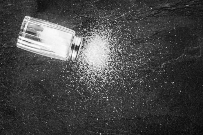 Salt shaker on black stone table. Sea salt on dark background.