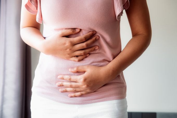 Woman is Having Stomach Ache or Menstrual Period, Close-Up Portrait of Young Woman is Suffering From Abdominal Pain at Her Home. Healthcare and Medicine Concept.