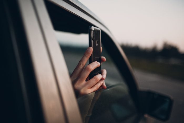 Girl takes pictures on the phone from the car window